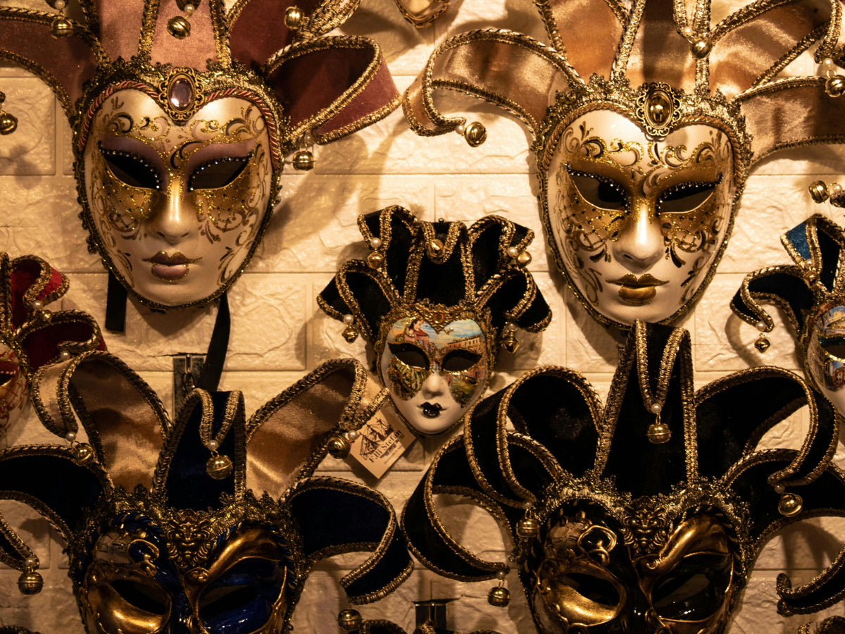 A wall of handcrafted Venetian masks in gold, black, and velvet — the romantic history of the masquerade ball and the mystery behind the mask
