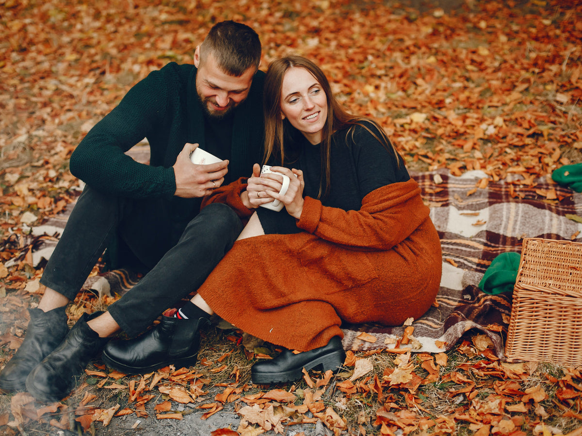 A couple holding hands on an autumn evening among falling leaves — the timeless hope behind every old Halloween love ritual